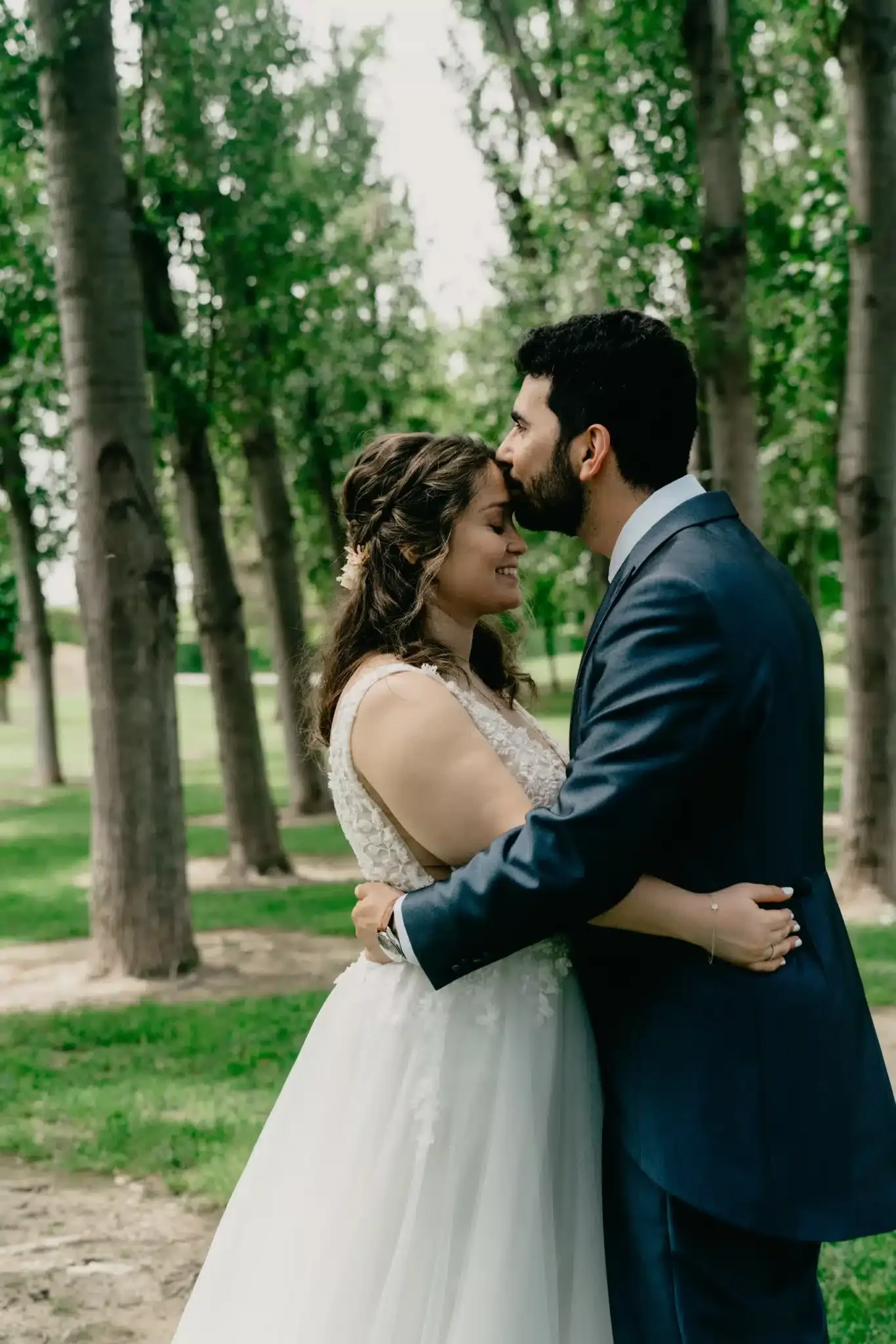Un beso en la frente durante el paseo de los novios por el bosque