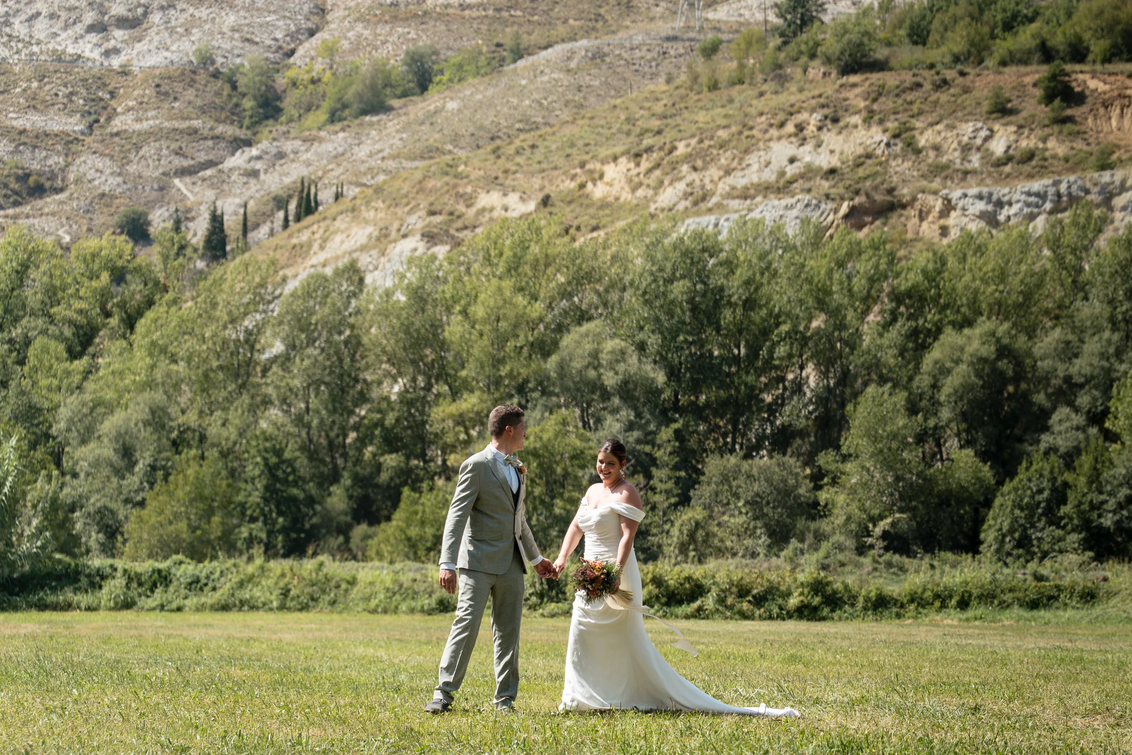 Novios caminando juntos entre montañas y prados