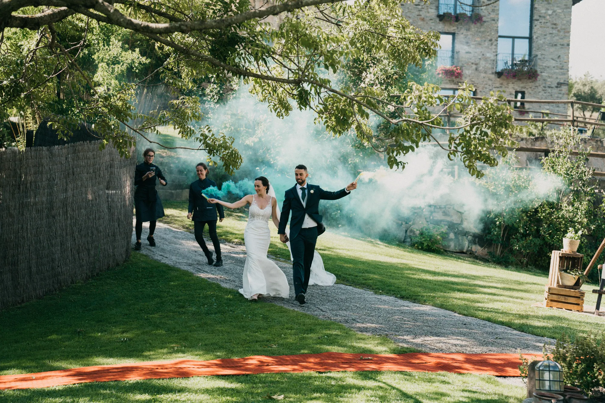 Los novios entran corriendo de la mano entre nubes de humo azul en su celebración